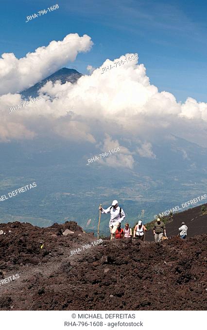 Climbing Pacaya volcano, with Fuego Volcano in distance, Antigua, Guatemala, Central America