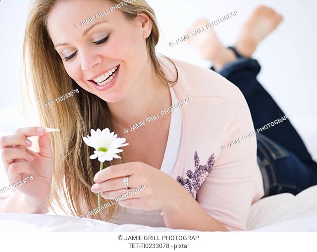 USA, New Jersey, Jersey City, Young attractive woman pulling petails out of flower head