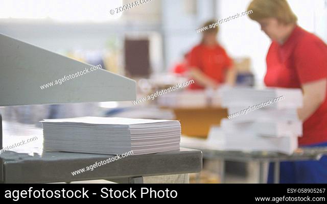 Paper stack in front of worker in the typography, blurred