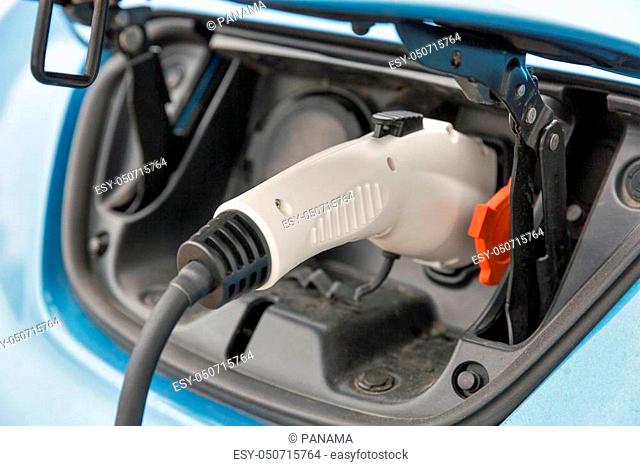 Charging an blue electric car closeup