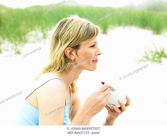 A woman eating on a beach