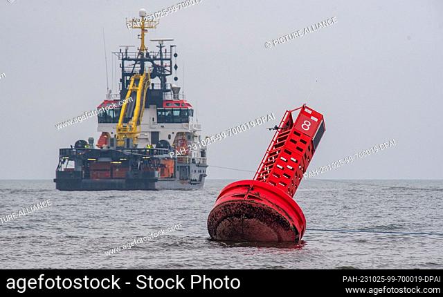 25 October 2023, Mecklenburg-Western Pomerania, Koserow: Under the gaze of numerous onlookers, a several meter tall navigation buoy was recovered from the beach...