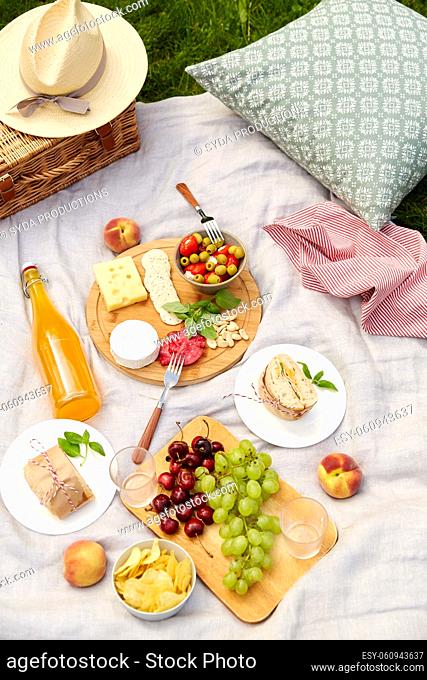 food, drinks and picnic basket on blanket on grass