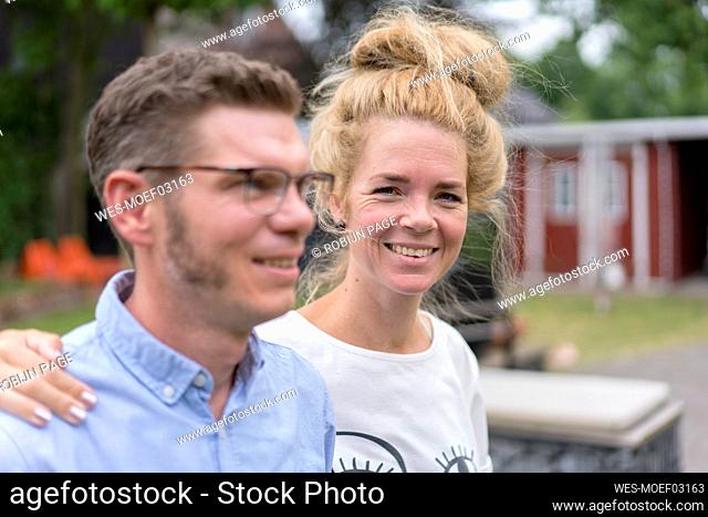 Smiling blond woman with hand on man's shoulder at back yard
