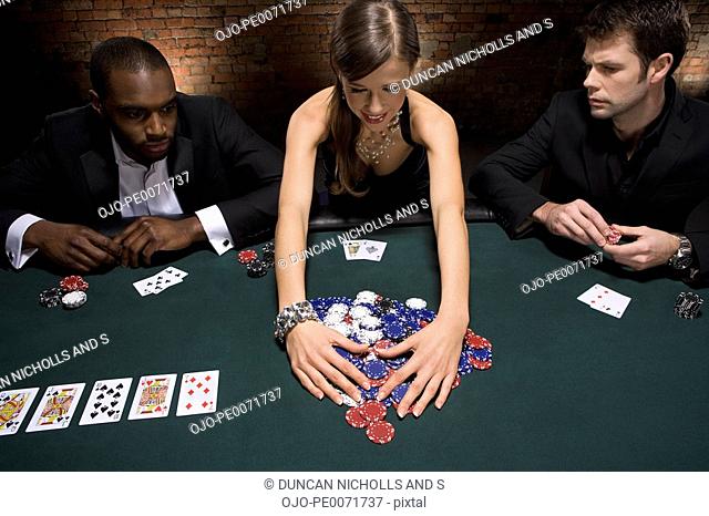 Woman gathering poker chips in casino