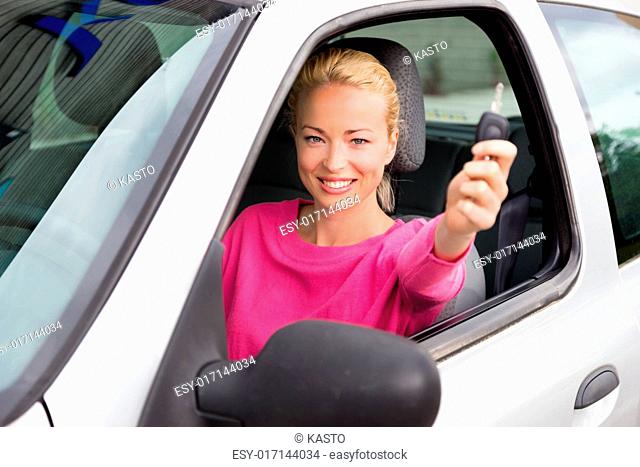 Woman driver showing car keys. Young female driving happy about her new car or drivers license. Caucasian model