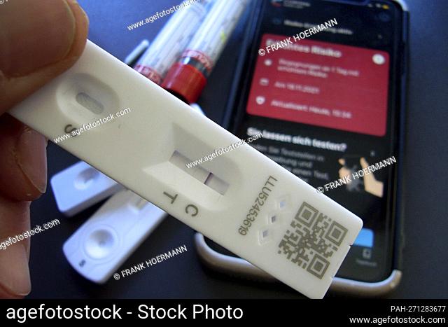 Topic image: Corona quick test after risk encounter (symbolic photo). The Corona Warn app on a smartphone shows increased risk
