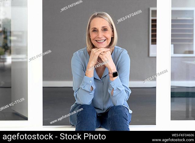 Smiling senior businesswoman with hands on chin in office
