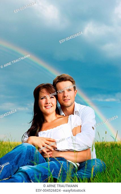 Glückliches Paar sitzt auf einer Wiese