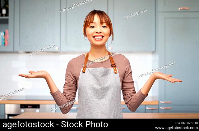 happy smiling woman in apron in kitchen at home