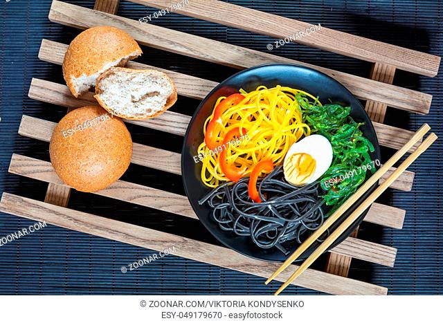 Hiyashi wakame with sesame and nut sauce, black and corn noodles, boiled egg. Bran bread. The rustic wooden lattice, black makisu
