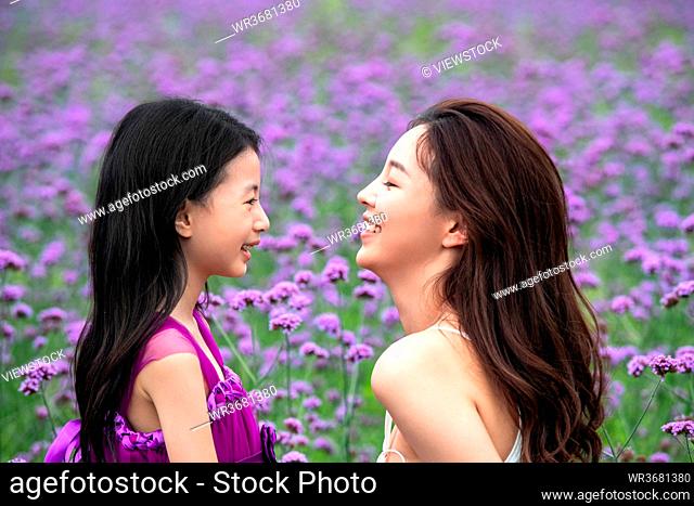 Happy mother and daughter playing in the flower sea