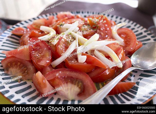Tomato simple salad with chopped onion, olive oil and oregano. Closeup