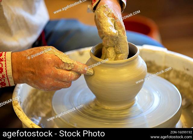 The hands of an artisan make a clay pot. Making clay products