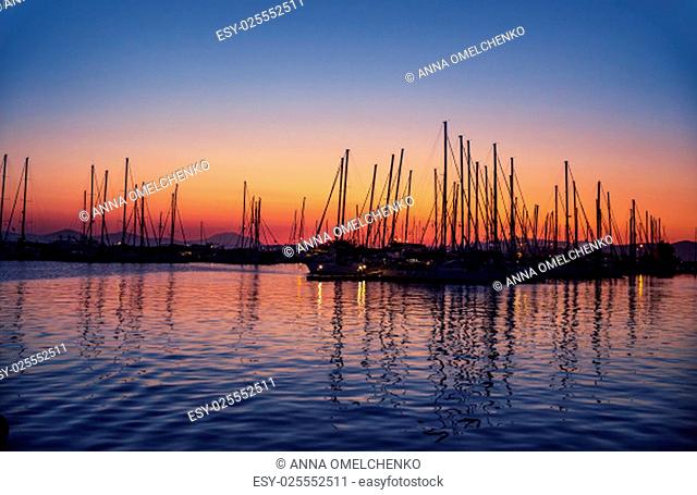 Harbour on sunset, silhouettes of luxury sailboat moored in the port in the evening, beautiful coastal view, active summer vacation