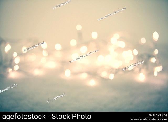 Christmas lights liying on the snow outdoors. Defocused abstract winter background for holiday