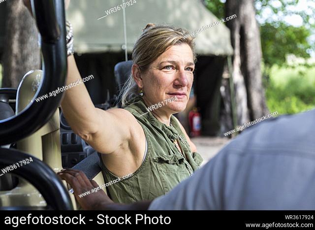 portrait of adult woman leaning on safari vehicle, tented camp, Botswana