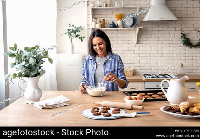 Woman holding egg while preparing food in kitchen at home