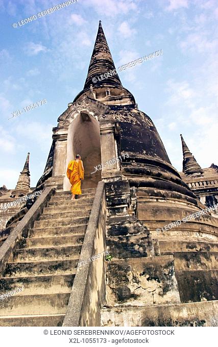 Buddhist monk on the stairs of chedi in Wat Phra Si Sanphet, a Buddhist temple in Ayutthaya, Thailand