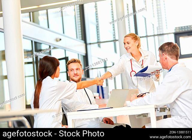 Junge Ärztin begrüßt Kollegen im Team mit handshake in einer Besprechung im Büro