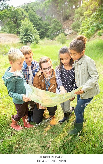 Students and teacher reading map in field
