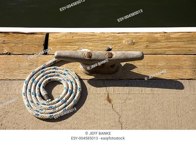 Rope coiled up attached to cleat awaiting boat to dock