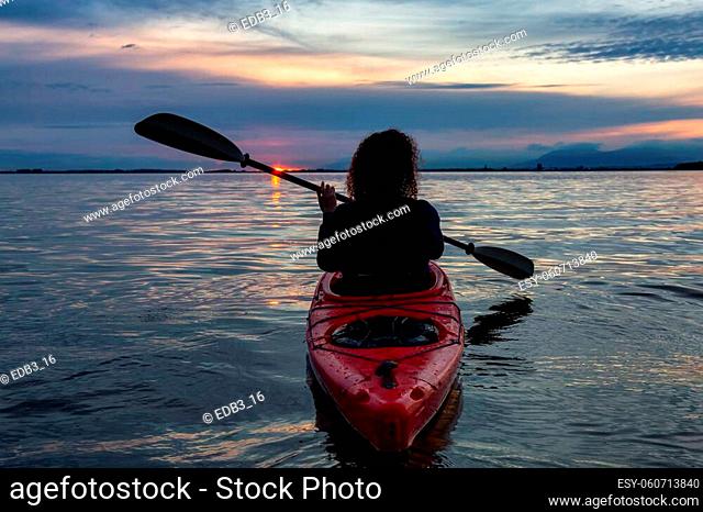Sea Kayaking in calm waters during a colorful and vibrant sunset. Adventure in Red Kayak. Location: White Rock, Vancouver, British Columbia, Canada