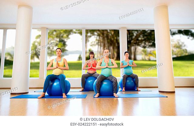 pregnancy, sport, fitness, people and healthy lifestyle concept - group of happy pregnant women exercising on ball in gym over natural window view background