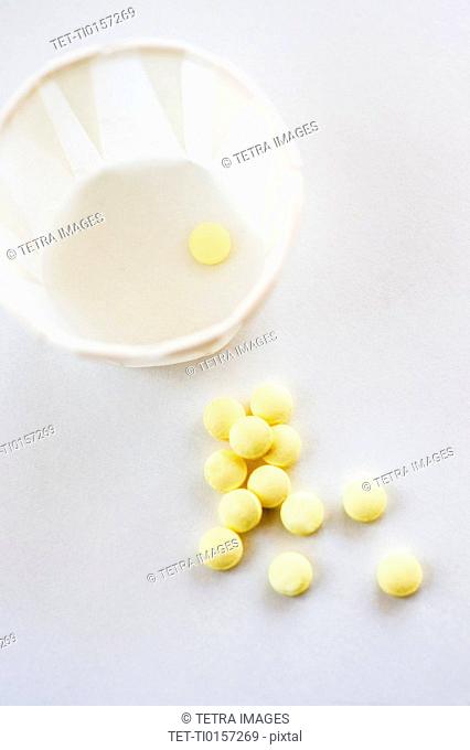 Yellow pills with cup, studio shot