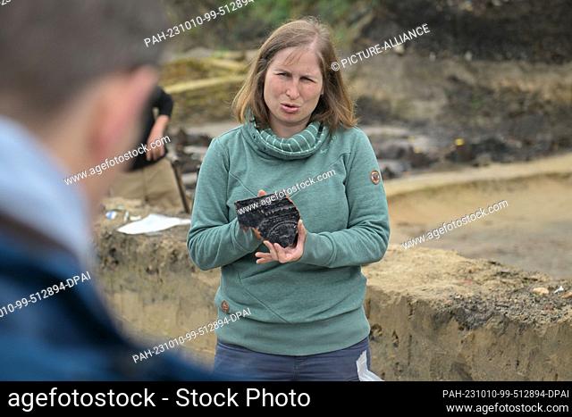 10 October 2023, Brandenburg, Potsdam: Archaeologist and excavation manager Julia Ebert shows a shard of a former tile stove found on the excavation site on the...