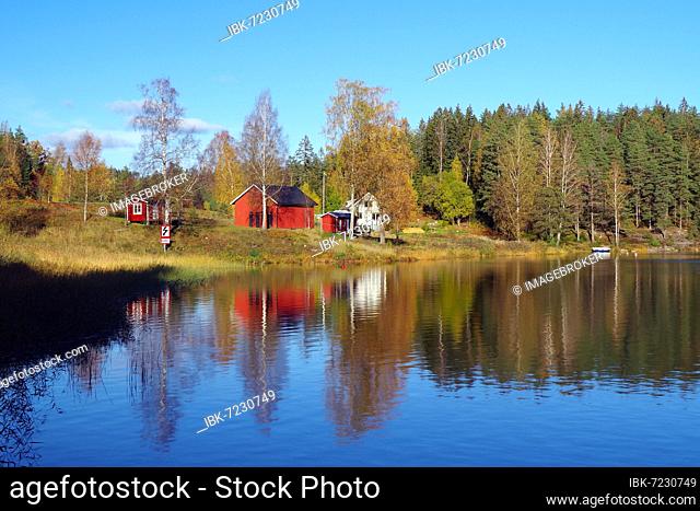 Small red house reflected in the calm water of a lake, autumn light, Bullaren, Bohuslän, Sweden, Europe