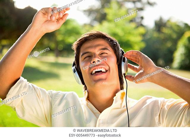 Man raising his arms while using headphones to sing along to music