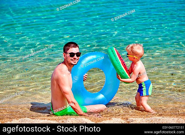Two year old toddler boy on beach with father