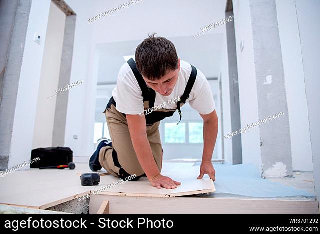 professional carpenter installing new laminated wooden floor in a unfinished apartment
