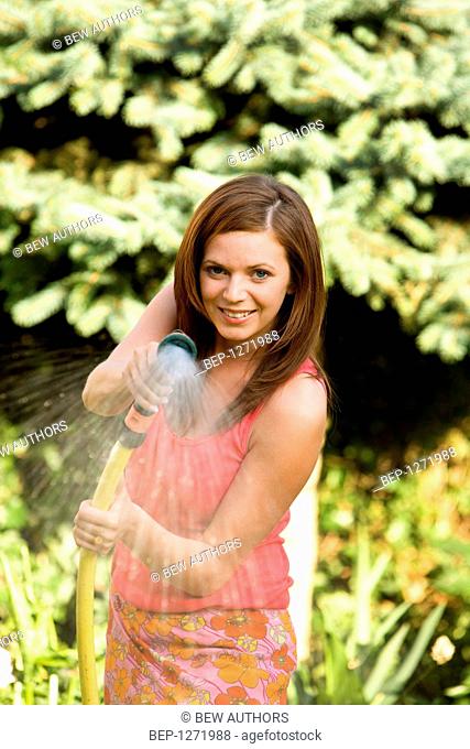 Woman watering garden with hose
