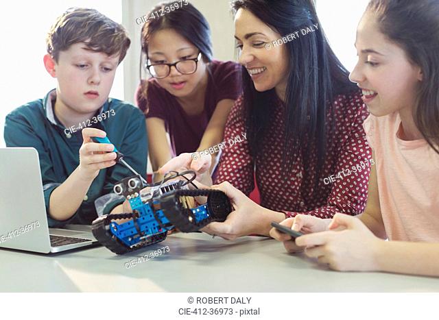 Female teacher and students programming and assembling robotics in classroom