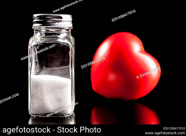 Heart and salt isolated on black background with reflection