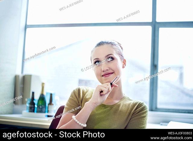 Smiling businesswoman thinking while sitting in board room at office