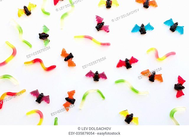 halloween, junk food and confectionery concept concept - multicolored gummy worms and jelly bet candies over white background