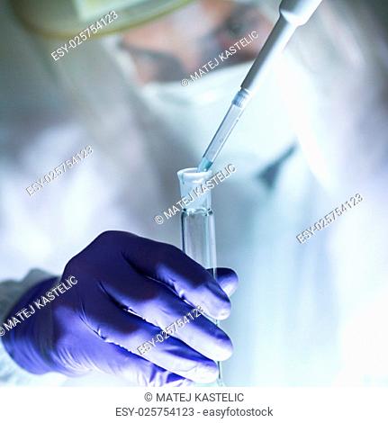 Life scientist researching in laboratory. Focused life science professional pipetting human serum media containing HIV infected cells