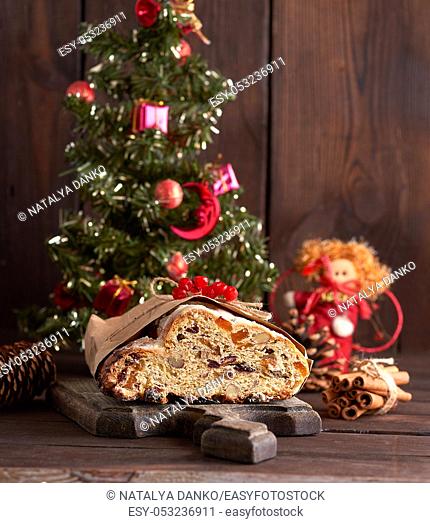 Stollen a traditional European cake with nuts and candied fruit, is dusted with icing sugar on a brown wooden board