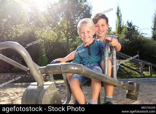 Two boys using digger on adventure playground in park