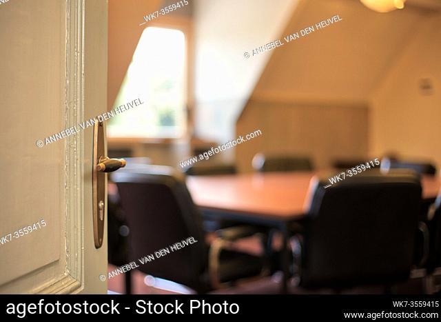 Door with handle opening to a blurred modern meeting room, office concept background empty