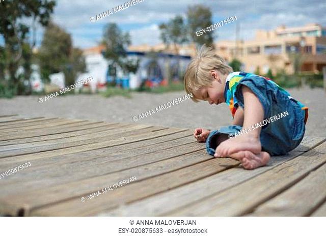 Boy playing on a wooden walkway on the beach