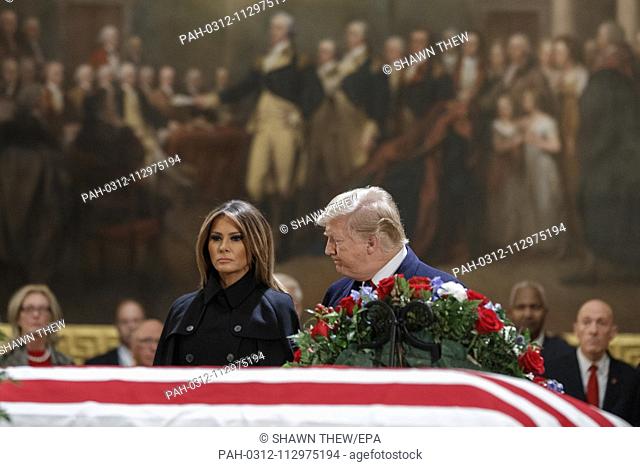 US President Donald J. Trump and First Lady Melania Trump take a moment of silence at the casket containing the body of former US President George H.W