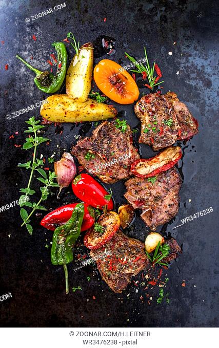 Barbecue T-bone lamb steak with Vegetable and seasonings as top view on a rusty metal sheet