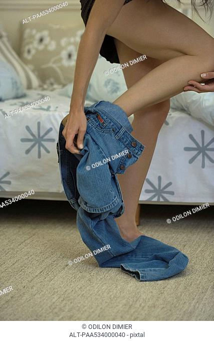 Woman taking off jeans, cropped, low angle view
