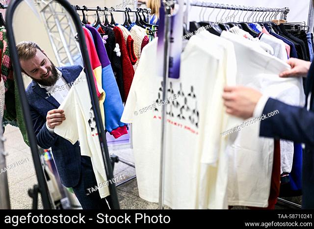 RUSSIA, MOSCOW - APRIL 28, 2023: A man looks at T-shirts on a clothing rack during the Moscow Fashion Week at the Oceania Shopping Centre