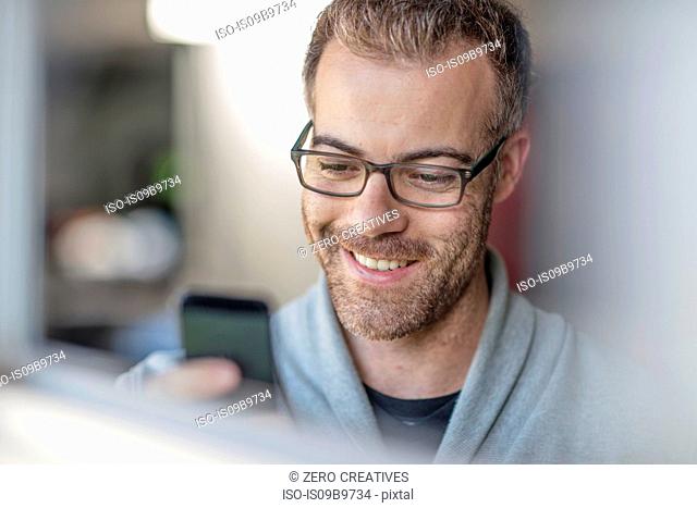 Happy businessman looking at smartphone at home