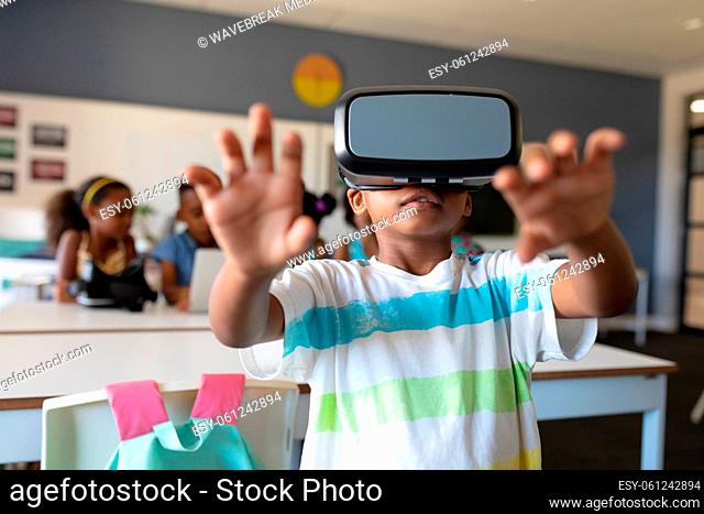 African american elementary schoolboy gesturing while wearing vr glasses in classroom